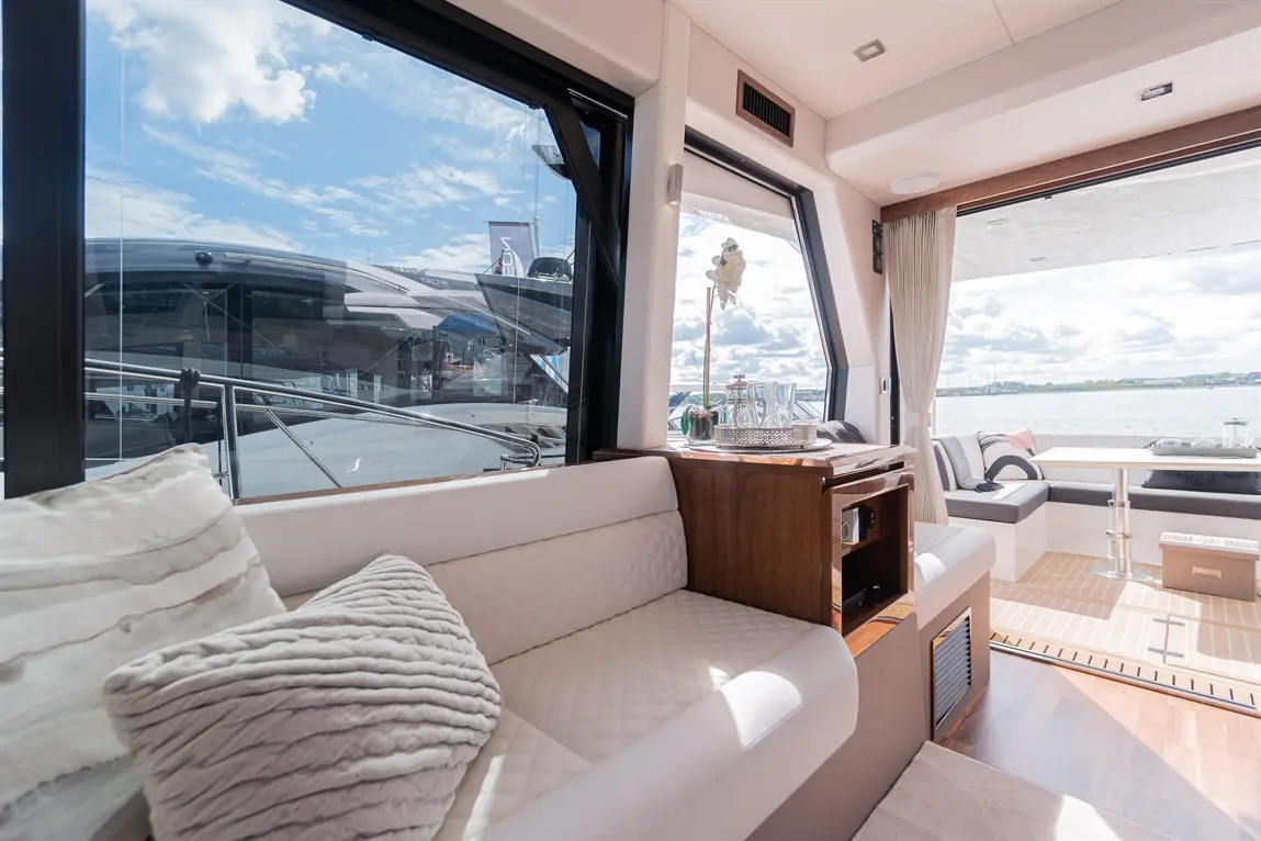 Bright interior of a luxury yacht, featuring plush seating, stylish decor, and panoramic windows overlooking the water.
